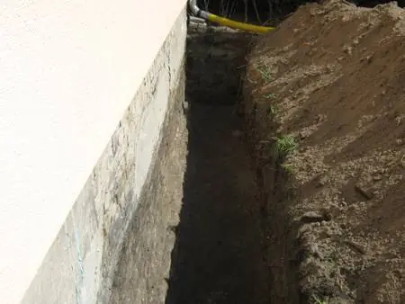 Ausgeschachteter Graben an einer Kellerwand vor der Abdichtung