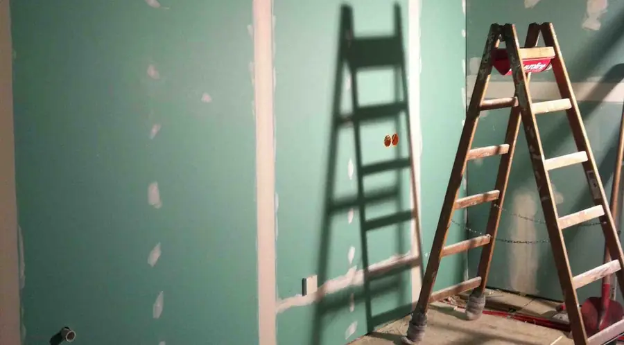 Trockenbauwand mit grünen Platten und einer Leiter auf einer Altbau-Baustelle
