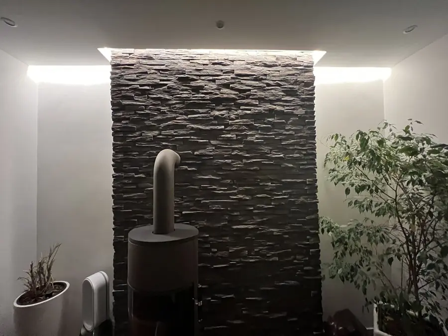 Sanierter Altbau-Wohnraum mit Natursteinwand und Kaminofen