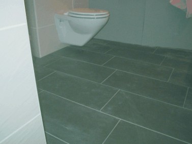 Bad mit grauen Bodenfliesen im Format 60 × 30 cm und Hänge-WC