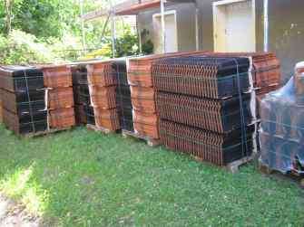 Paletten mit neuen Tondachziegeln im Garten vor dem Altbau