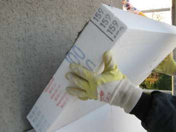 Handwerker setzt eine Polystyrol-Dämmplatte an die Giebelwand des Altbaus