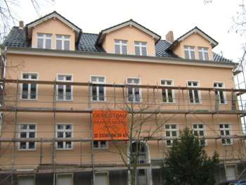 Frisch verputzte Fassade eines Altbau-Mehrfamilienhauses mit drei Gauben beim Abbau des Gerüsts