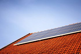 Photovoltaikanlage auf einem roten Ziegeldach vor blauem Himmel